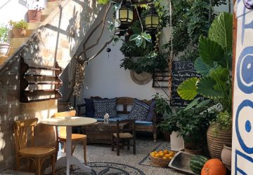 a patio with a table, chairs, and potted plants